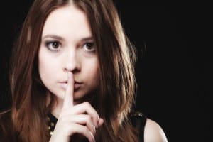 Secret woman finger on lips. Teen girl showing hand silence sign, saying hush be quiet on black