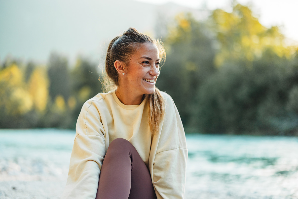 testimonial-bg Smiling woman sitting outdoors by the water